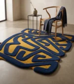 Storm Over Sahara hand tufted rug in navy blue and mustard yellow with abstract maze pattern styled on concrete floor with Wishbone chair, navy throw, black steel side table and ceramic vase — luxury shaped area rug