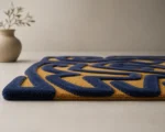 Close-up of Storm Over Sahara hand tufted rug showing raised navy blue wool pile maze pattern against mustard yellow background — sculptural high-low pile texture detail with organic shaped border edge